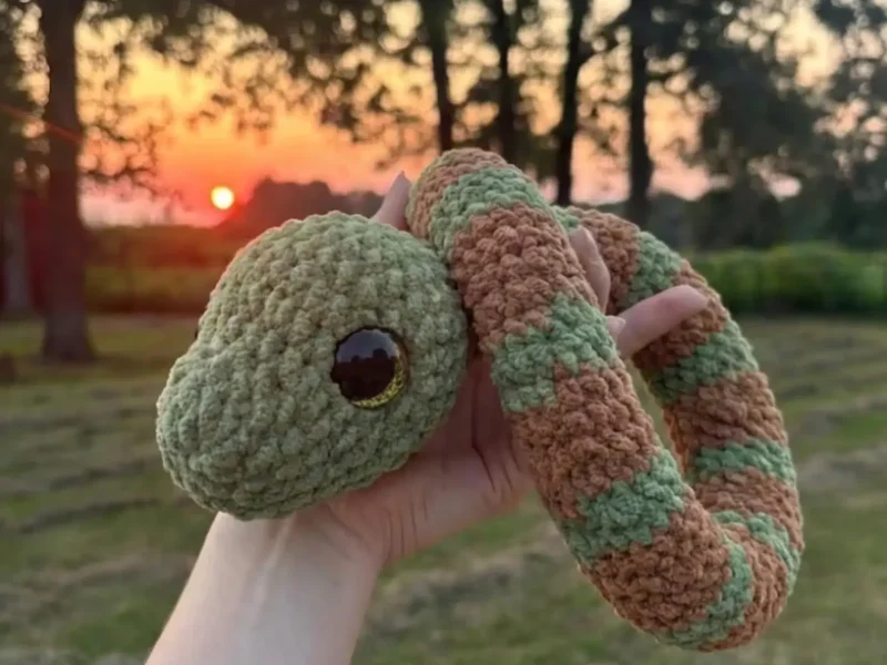Crochet snake amigurumi with coral colourwork bands